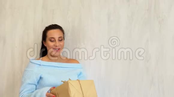 怀了孕的妈妈拿着白色圣诞礼物站在圣诞树旁视频的预览图