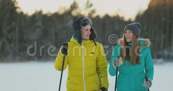 在冬天的森林里滑雪时用慈爱的眼睛看着对方一对已婚夫妇过着健康的生活方式视频的预览图