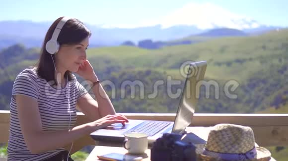 女孩博主在山上背景的笔记本电脑上打字慢潮视频的预览图