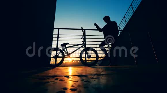 夕阳下一个年轻人和他的自行车的剪影视频的预览图