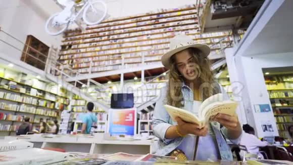 一个漂亮的年轻女人在书店看书视频的预览图