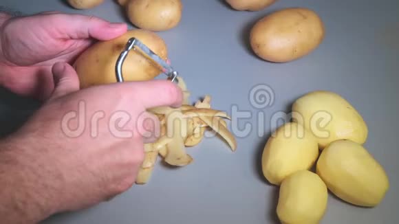 男性手用厨房削皮机削土豆慢动作视频的预览图