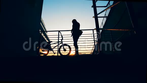 夕阳西下的平台上一个年轻人在做头发一辆自行车站在他旁边视频的预览图