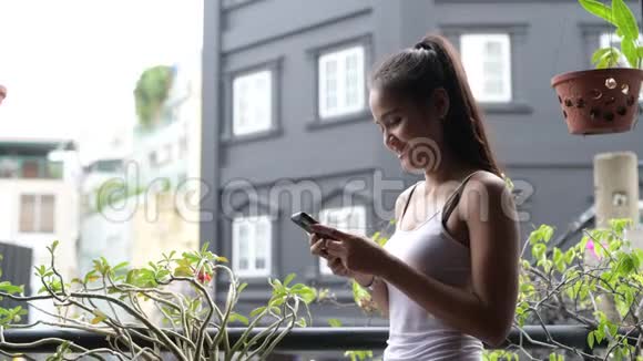 使用手机在阳台上的美丽亚洲女人户外视频的预览图