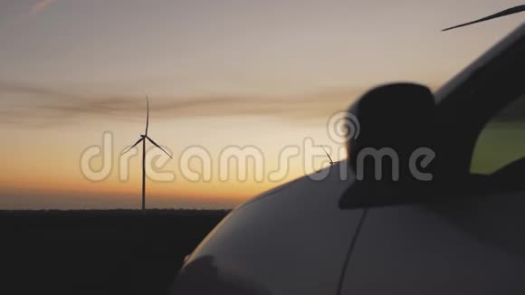 日落时分汽车背景上的风力发电厂视频的预览图