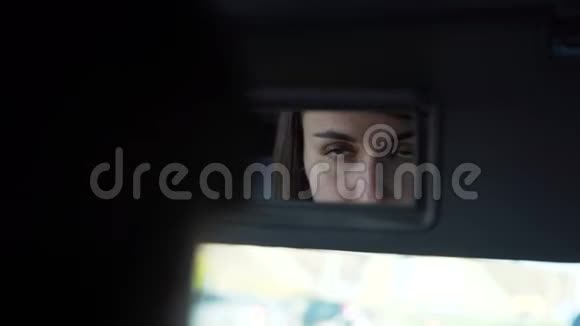 漂亮的女人把头发固定在汽车的镜子里视频的预览图