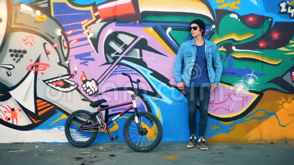 男青少年正骑着自行车站在涂鸦墙上视频的预览图