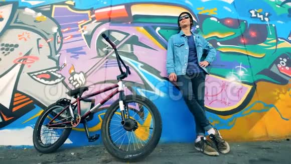 男骑自行车的人靠在涂鸦墙上自行车就在它附近视频的预览图