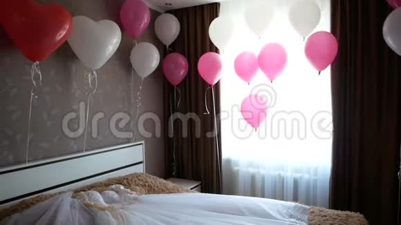 带粉色和白色气球的新娘房间床上有礼服视频的预览图