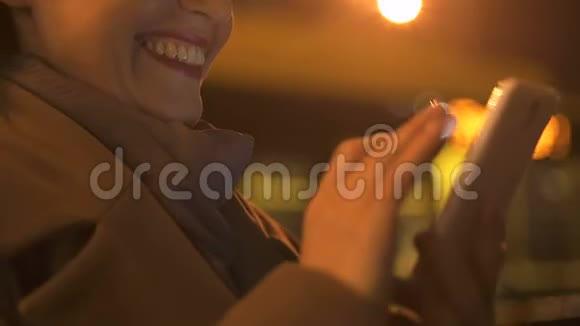 微笑快乐的女性看有趣的照片滚动智能手机应用程序视频的预览图