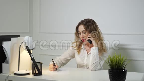 年轻的女秘书正在用手机说话和做笔记办公室工作理念视频的预览图