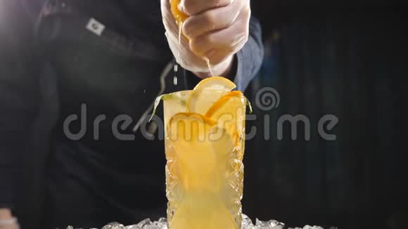 特写厨师将橙子以慢动作挤压到新鲜水果鸡尾酒上果汁从水果里滴出来烹调视频的预览图
