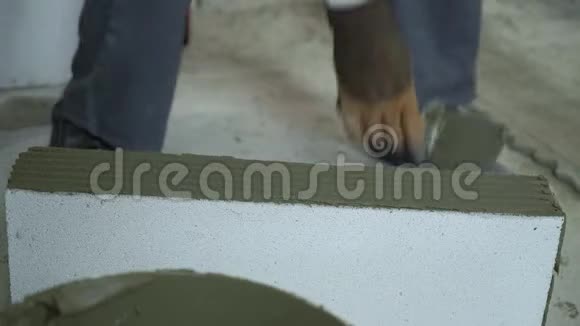 建筑工人从加气混凝土砌块两侧清除过多的砂浆视频的预览图