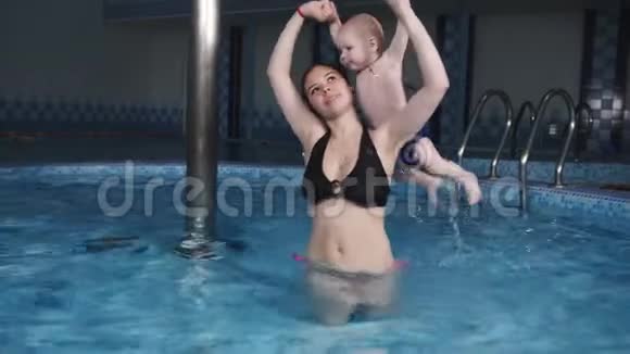 幼儿水上体操妈妈和他的小儿子在健身中心的游泳池里做体操视频的预览图