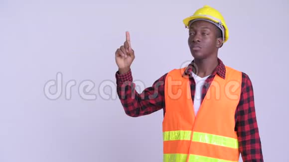年轻快乐的非洲男子建筑工人一边思考一边指出视频的预览图