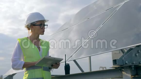 一位女建筑工人站在太阳能电池附近用平板电脑工作视频的预览图