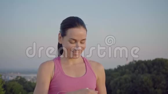 城市背景上一个迷人女孩的肖像穿紫色T恤的女运动员从瓶子里喝水视频的预览图