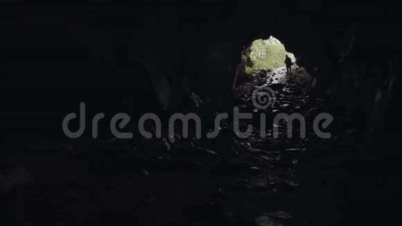 地下洞穴探险者的剪影后面有入口旅游和自然概念库存数据视频的预览图