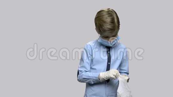 戴手术面罩的男孩戴上橡胶手套视频的预览图