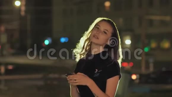 年轻女孩在夜间城市使用智能手机和发送短信的肖像视频的预览图