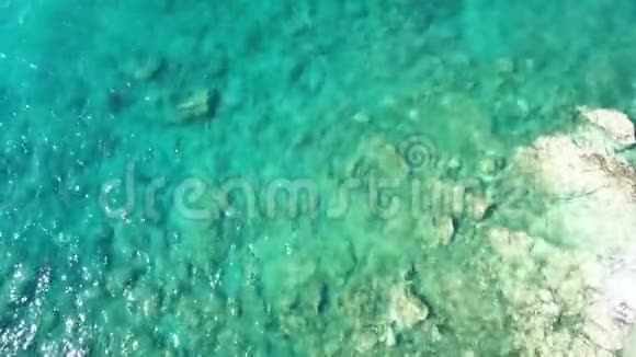 在清澈的蓝水下岩石海岸海浪的空中影像视频的预览图