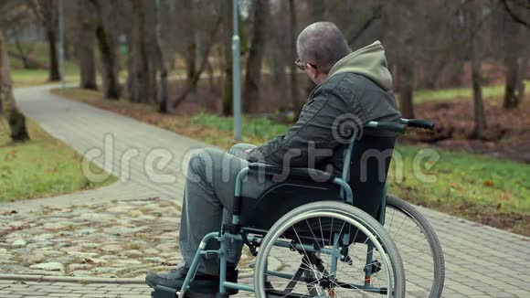 坐轮椅的残疾人在公园的小路上等待救助视频的预览图