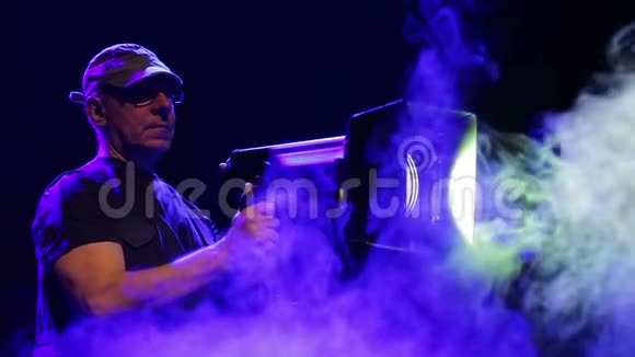 舞台上的一个人在烟雾缭绕中用一台剧场的投影仪工作视频的预览图