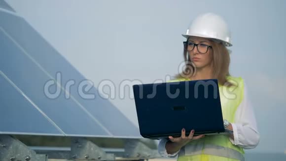 漂亮的女职员正拿着笔记本电脑在太阳能电池附近行走视频的预览图