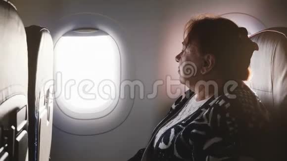 快乐的欧洲高级女飞机乘客在度假时坐在靠窗的座位上欣赏风景视频的预览图
