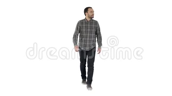 放松的休闲男子穿着牛仔裤和衬衫走路看着两边的白色背景视频的预览图