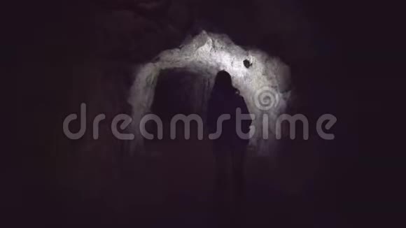 女孩旅行者带着背包手里拿着手电筒去洞穴后景视频的预览图