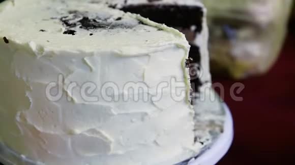 人类的手在用白色奶油装饰的大巧克力蛋糕上旋转视频的预览图