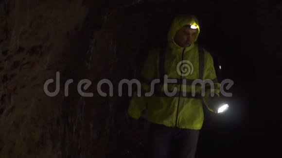 一名志愿者手里拿着手电筒额头上拿着手电筒在黑暗的洞穴里寻找一个失踪的人视频的预览图