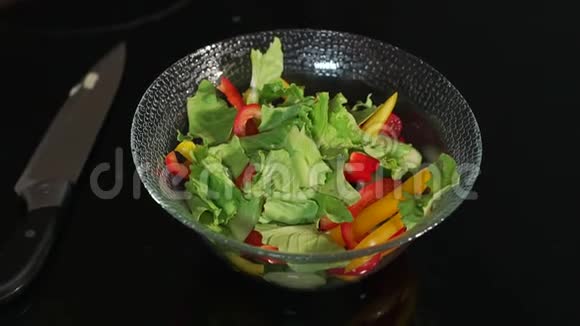 女孩准备一份蔬菜和生菜沙拉在黑色背景下特写视频的预览图