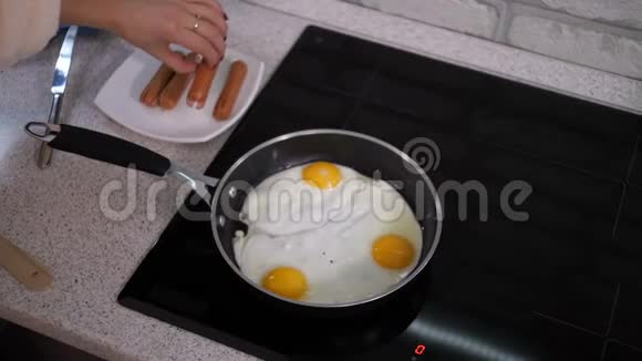 女孩在煎锅里炒鸡蛋把香肠加进去4K慢慢视频的预览图