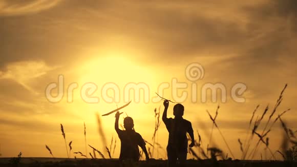 日落时分两个男孩和飞机一起奔跑的剪影视频的预览图