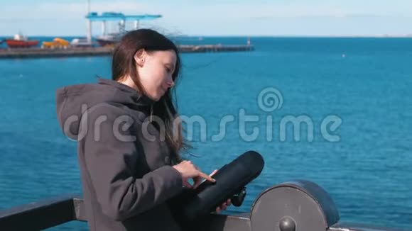 女人从热水瓶里倒茶在水边喝酒年轻的黑发女人在旅途中视频的预览图