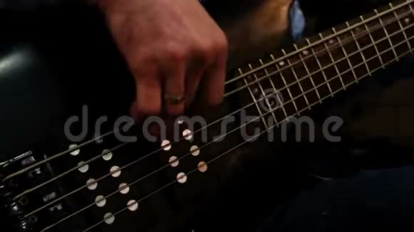 音乐家低音吉他手那人用右手拨动琴弦左手夹住乐弦视频的预览图