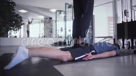 在健身房里男人的腿踩在躺着的男人的背上视频的预览图