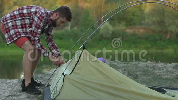 职业男性徒步旅行者在河边搭帐篷野营度假旅行视频的预览图