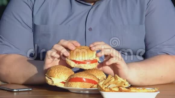 肥胖的饥饿男人吃肥大的汉堡不健康的食物成瘾超重视频的预览图