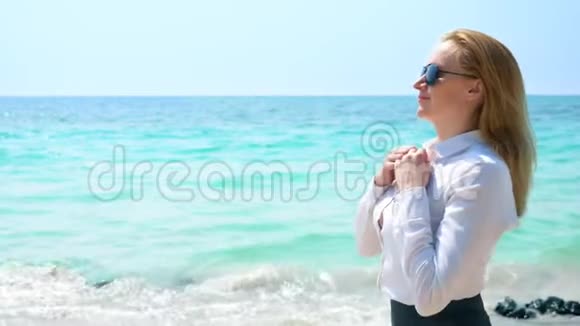 海滩上的女商人她喜欢看海她解开衬衫的扣子在海中呼吸视频的预览图