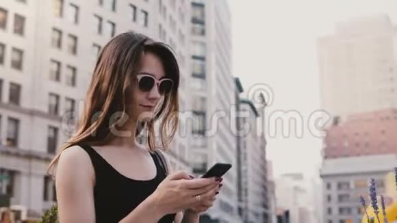 兴奋的白人年轻旅游妇女带着戴着太阳镜的智能手机在纽约四处张望这是一个惊人的恐慌镜头视频的预览图