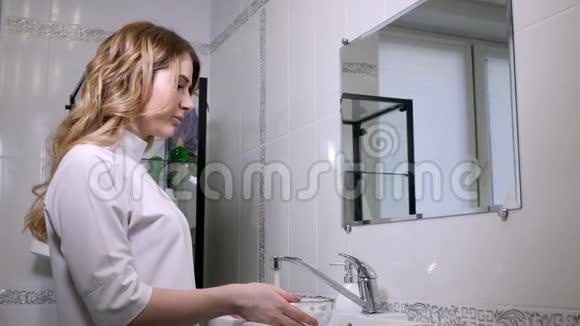 身穿长袍的女医生美容师把水倒进一个大碗里洗脸视频的预览图