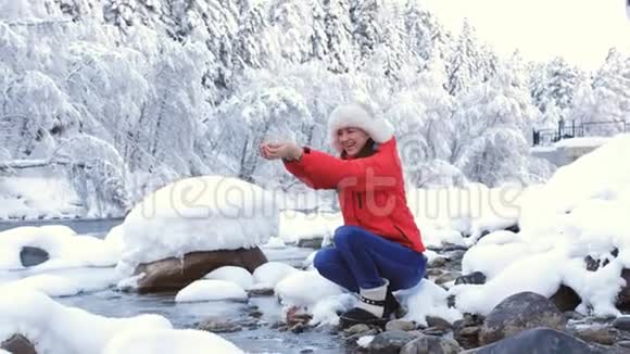 冬林中的女子坐在山间小溪旁舀着冰冷的水视频的预览图