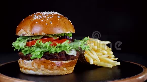 快餐食品Berger带炸薯条在黑色背景的木板上旋转视频的预览图