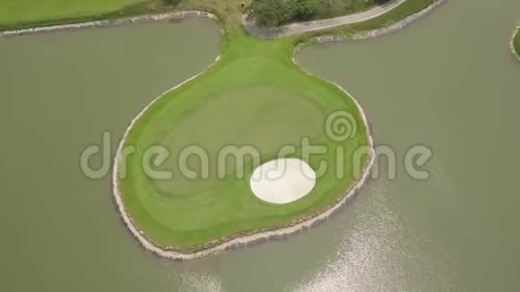 来自飞行无人机的高尔夫球场和湖泊景观在高尔夫俱乐部的池塘中鸟瞰岛上的绿色高尔夫球场视频的预览图