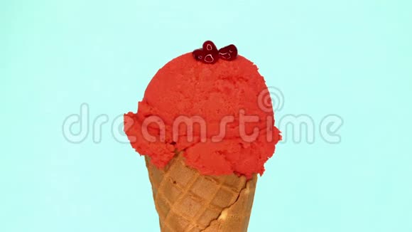 草莓冰淇淋在华夫饼锥旋转的蓝色背景和液体野生浆果浇在上面美味可口视频的预览图