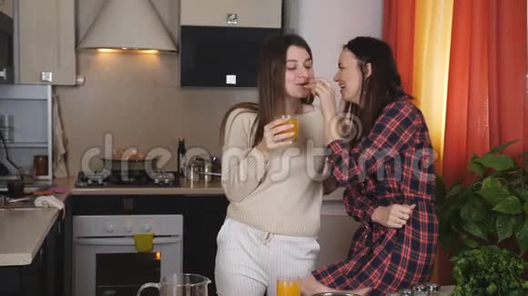 两个女人在厨房里喝橙汁互相喂水果视频的预览图