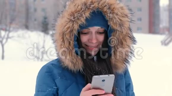 年轻漂亮的女人在手机上输入一条信息然后看着相机微笑着视频的预览图